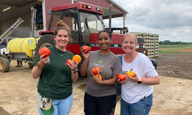 Three Loyola employees on a service trip at First Fruits Farm