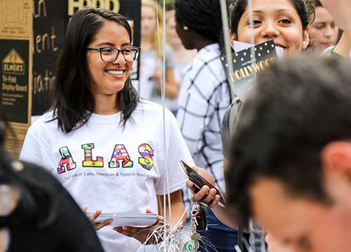 Students smiling and wearing a shirt that reads ALAS - Association of Latin American &amp; Spanish students