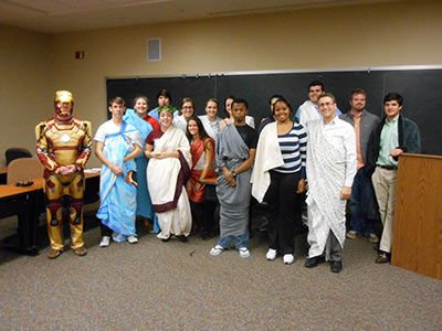 Students in classroom gather for group photo in costume