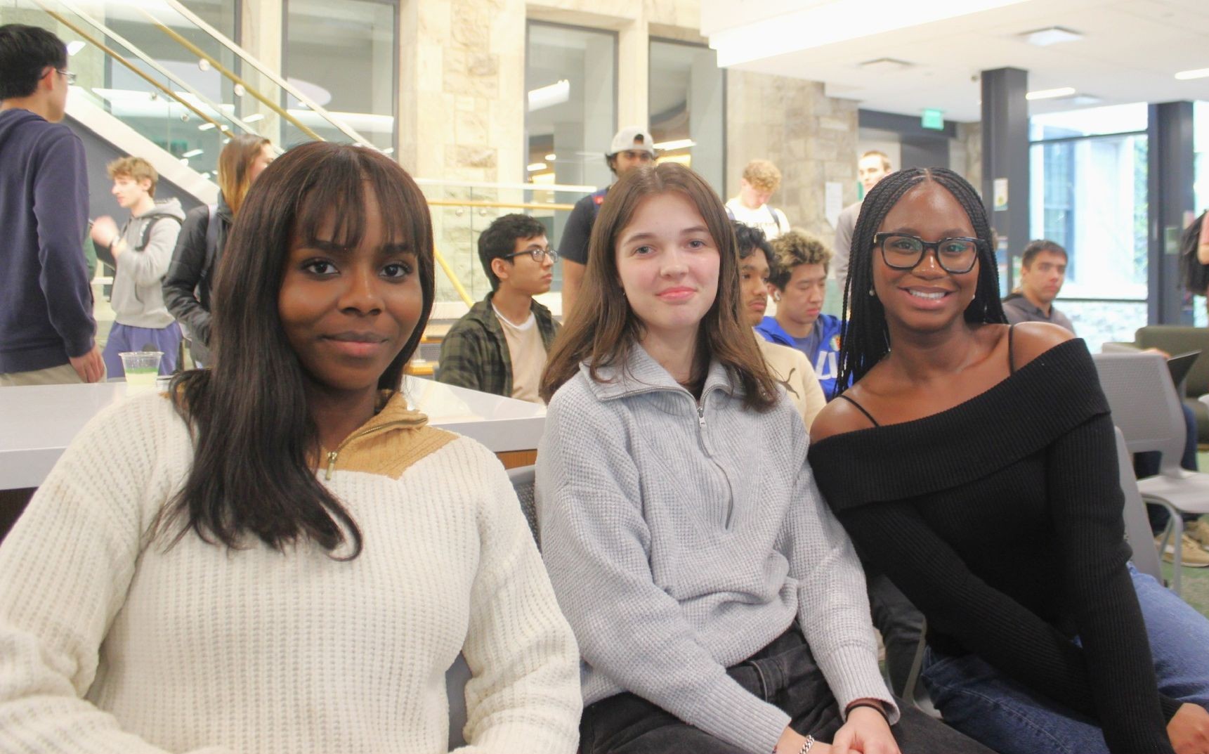 Three students sitting in the Rizzo Career Center smile together.