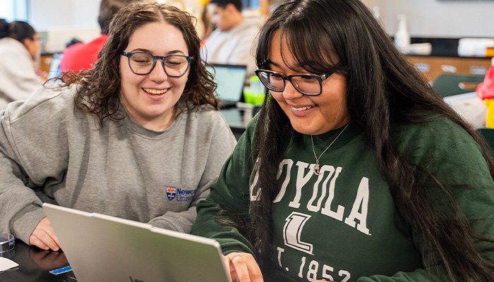 A student helps another student on her laptop