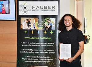 Chet Pajardo II posing next to the Hauber Fellowship sign with his paper