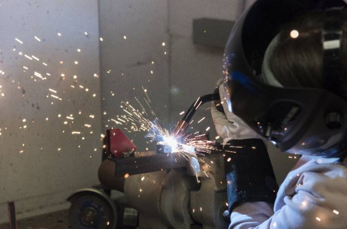 materials engineering student welding an object with sparks flying in the air