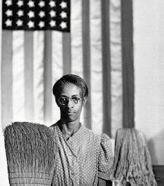 A Black woman hold a broom in front of an american flag