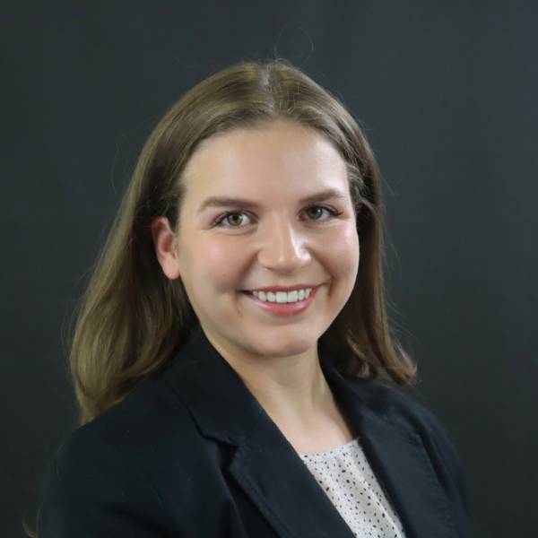 Annabella Bair headshot with black blazer and hair down on black background