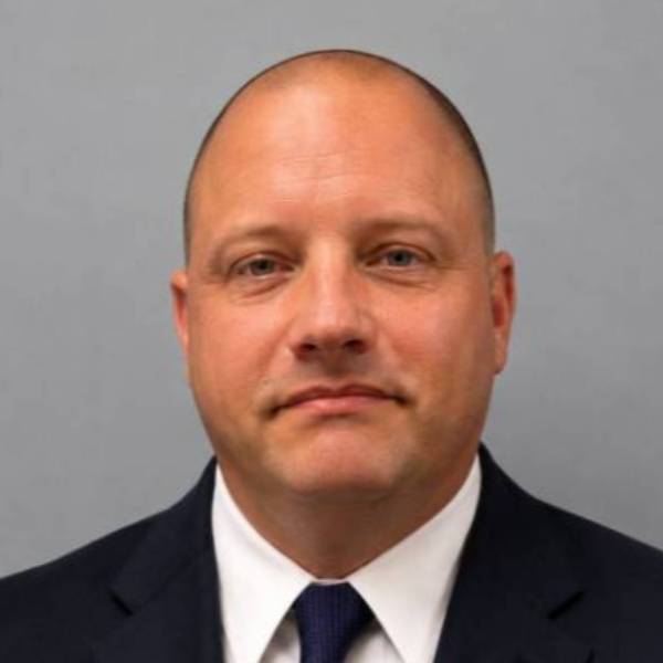 Headshot of Dr. Dom Bridges in blue suit, white shirt, and blue tie