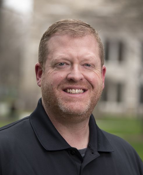 Jon Fried headshot in navy polo and blurred background