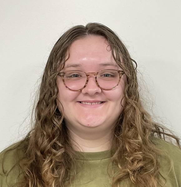 Lexi Giska headshot with green top and tortoiseshell glasses on white background