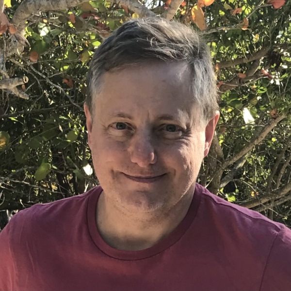 John Morgan headshot in burgundy tshirt with tree in background