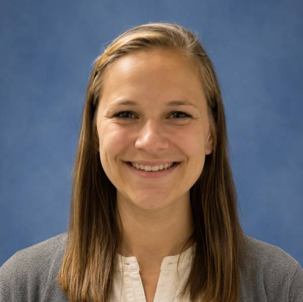 Kirby Povilaitis headshot in white top and grey cardigan