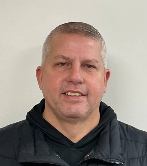 Wade Zufall headshot with black hoodie and vest on white background