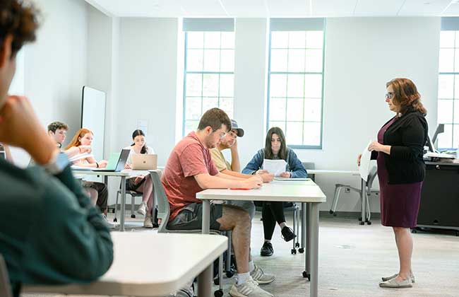 Students taking notes during a lecture in a bright classroom