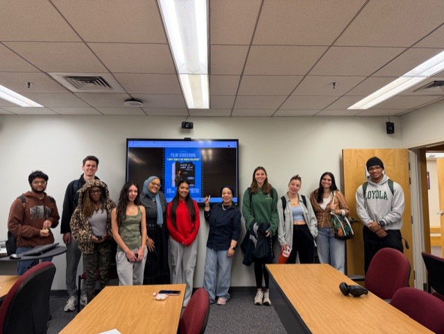 students posing in front of a tv