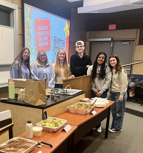 students posing with food at Italian club event