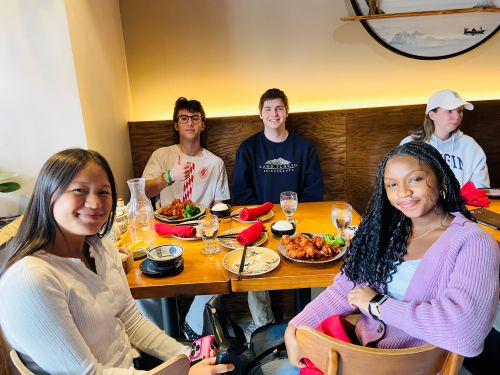 four Loyola students sitting at a table with several places of food