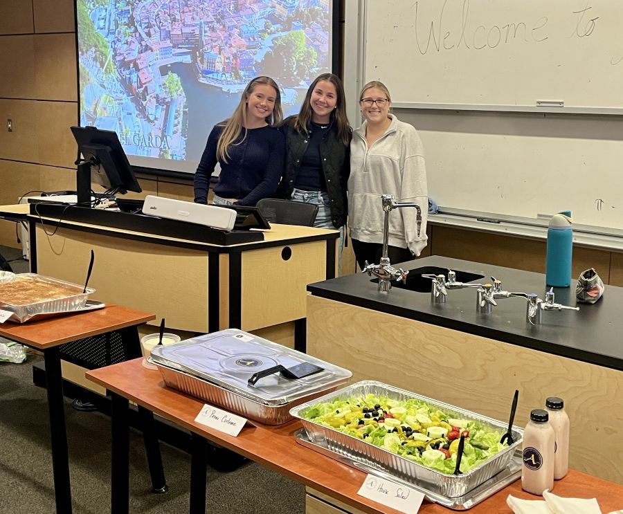 students posing in front of table of food