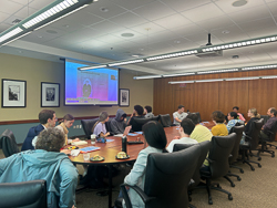 people around a table looking at a screen