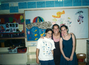 Dr Gawerc smiling with two children in a classroom