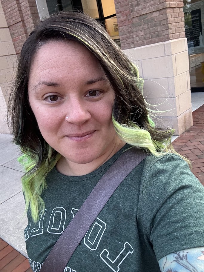 Jessi Ceiri standing in front of a brick building in a green Loyola T shirt