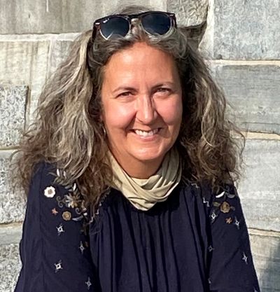 Dr. Kathleen Siren in front of stone building with sunglasses atop her head