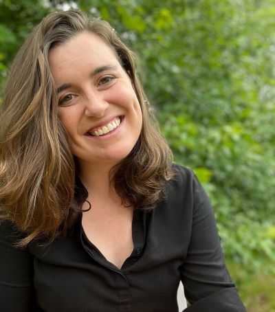 Emma Dries smiling at camera with green backdrop