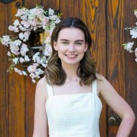 Katilin Quigley dressed in white and in front of wood door