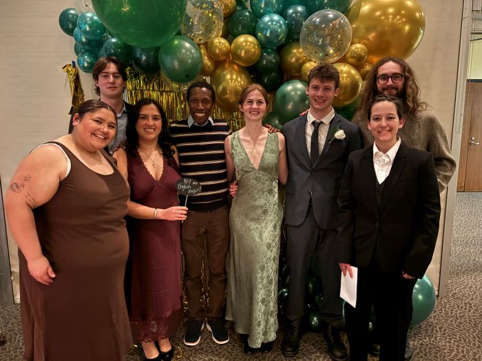 students and faculty posing for pictures in front of a balloon arch