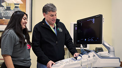 A nurse and a student working on an ultrasound machine