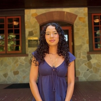Genesis smiles by a stone wall on the Humanities Building