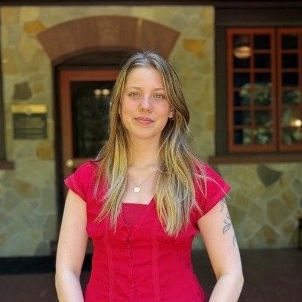 Ashlyn Shematek smiles on the large porch of the Humanities Building