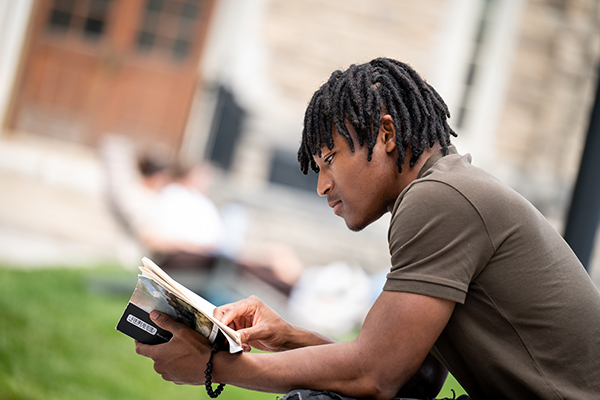 A Loyola student reads a book on the quad on a nice spring day