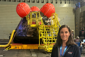 Lisa Mazzuca stands before NASA's Artemis II in a photo take with her cellphone