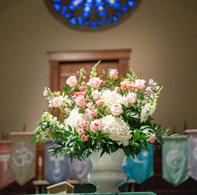 Flower arrangement below Alumni Chapel stained glass during HARPS 2025