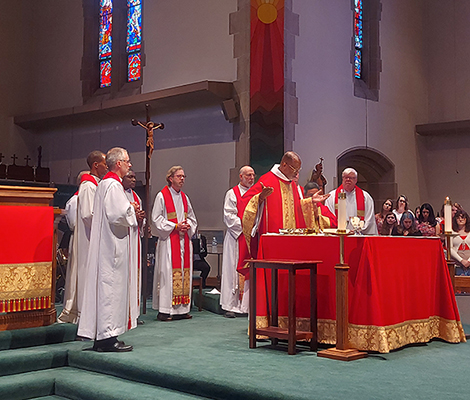 Jesuit community in red celebrating Mass
