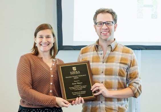 man with plaid shirt and woman with brown sweater holding a plaque