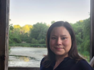 woman standing before pond and trees