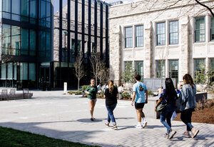 Student in green shirt walking backwards, giving a tour to four people.