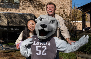 Two students posing with Loyola's mascot, Iggy.