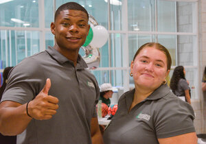 Two students posing, person on the left giving a thumbs up.