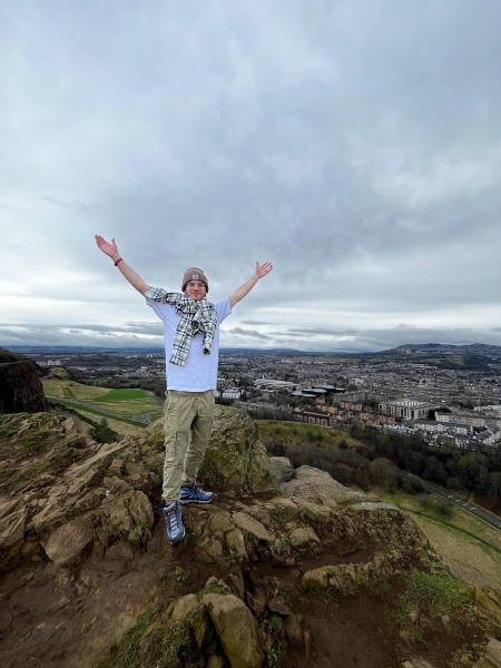 A boy with his hands up on a rock