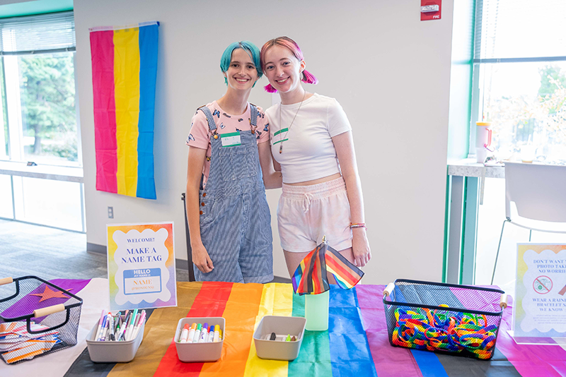 Two students pose at the LGBTQ+ Student Services table