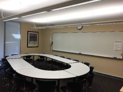 Tables arranged in oval, long whiteboard stretching across whole wall