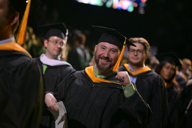 group of adult college students wearing caps and gowns