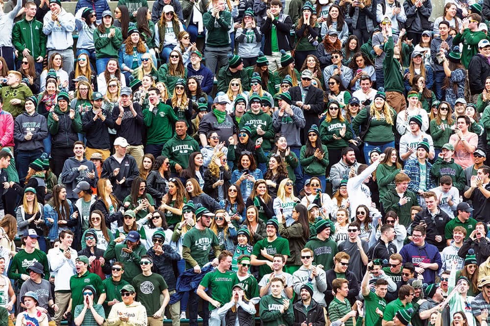 Loyola community at a sports game standing on bleachers