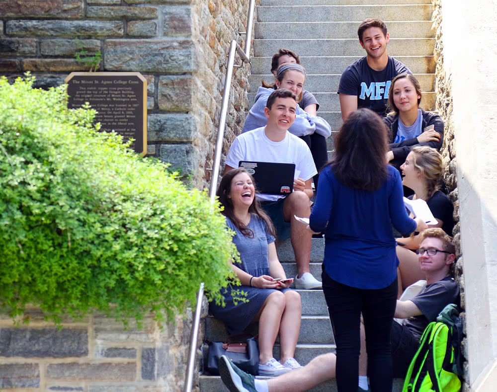 students sitting on steps outside receiving a lecture