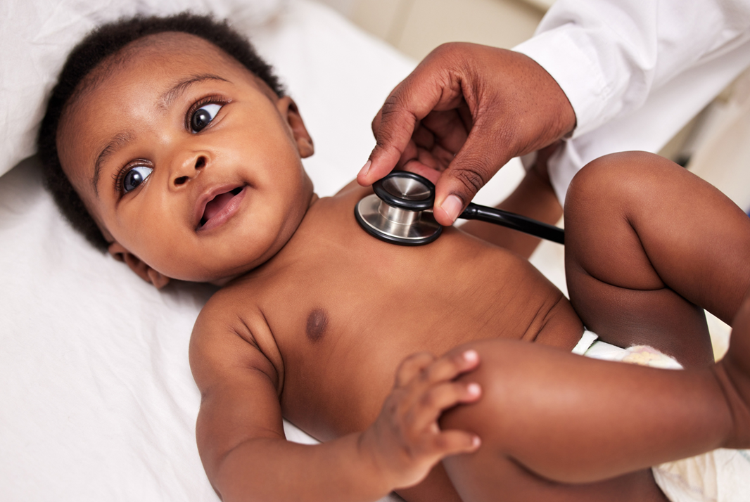 Baby lying on its back with a doctor using a stethoscope on its chest