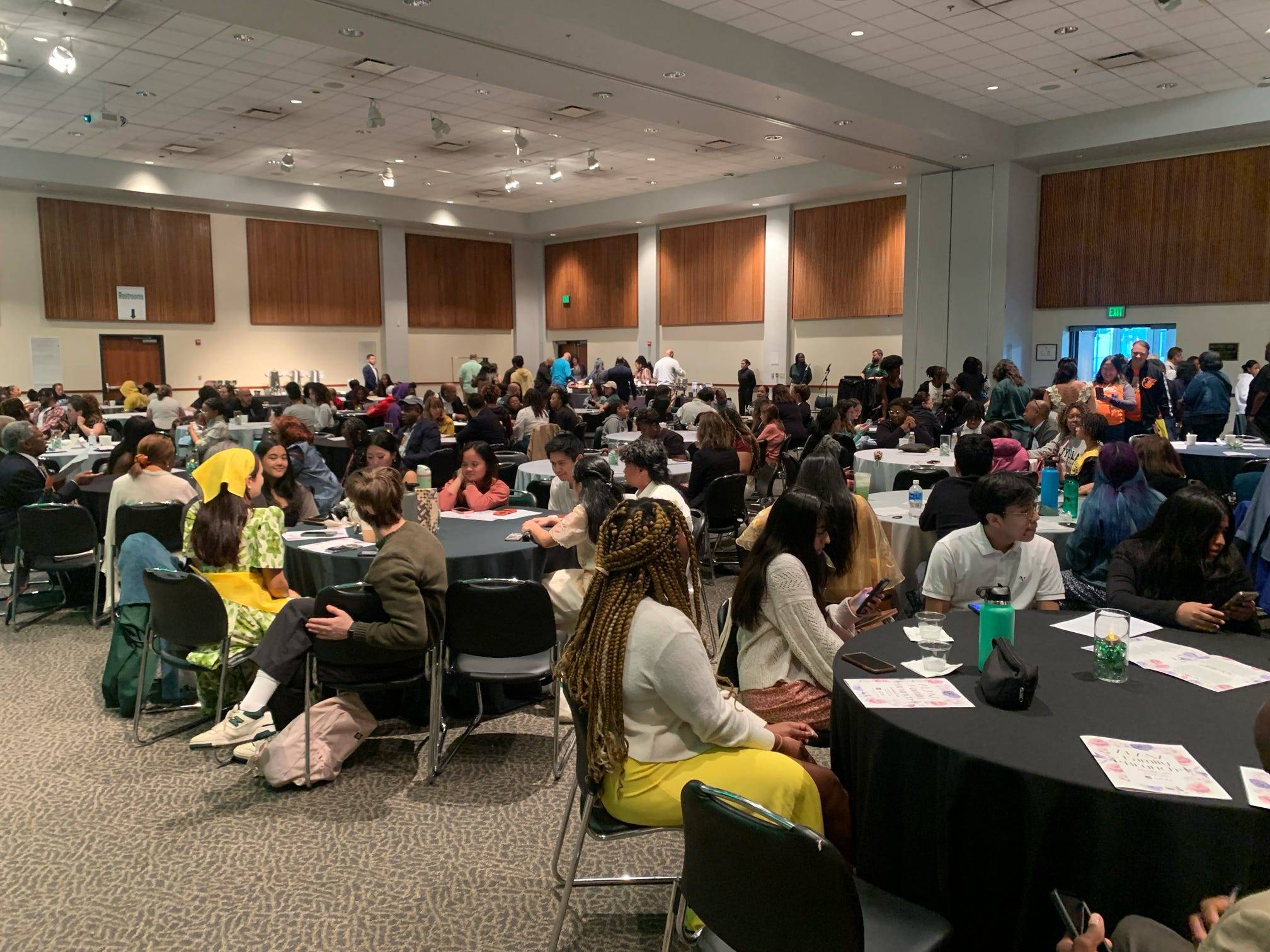 A room full of students and families sitting at round tables.