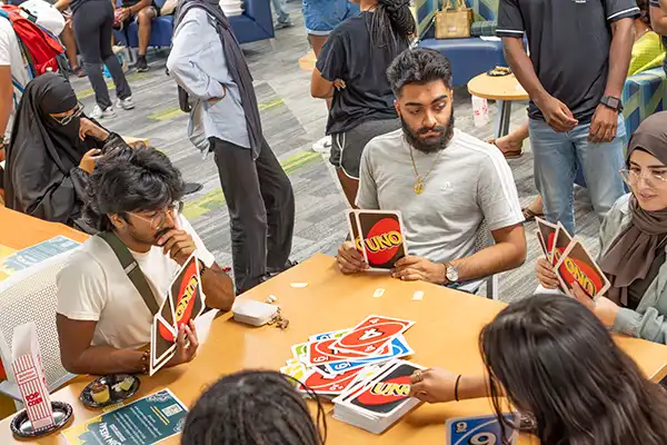 Students sit in a group playing the game Uno