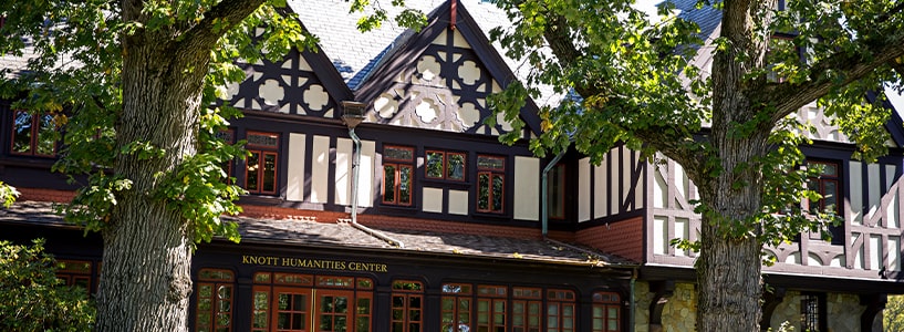 The facade of Loyola's iconic Tudor-style Humanities building with large, established trees in the foreground