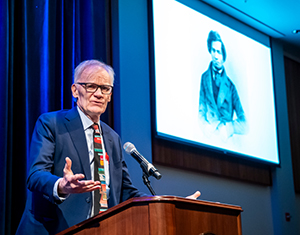 David Blight delivering keynote lecture with an image of Frederick Douglass behind him
